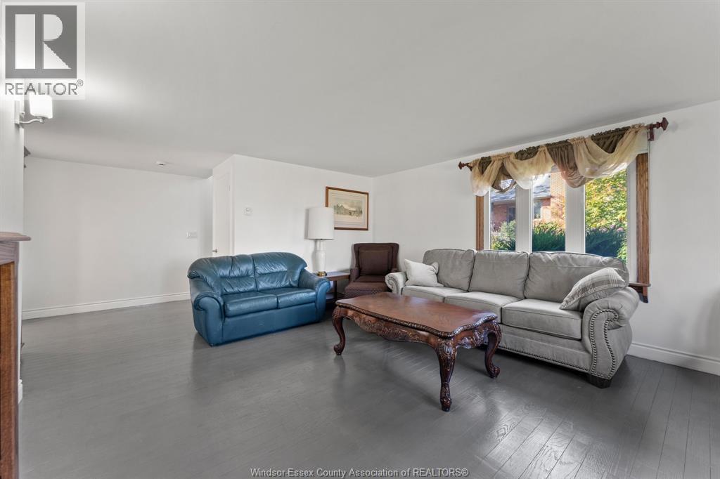 A living room with a blue leather couch, a brown coffee table, and a grey sofa with a throw blanket.