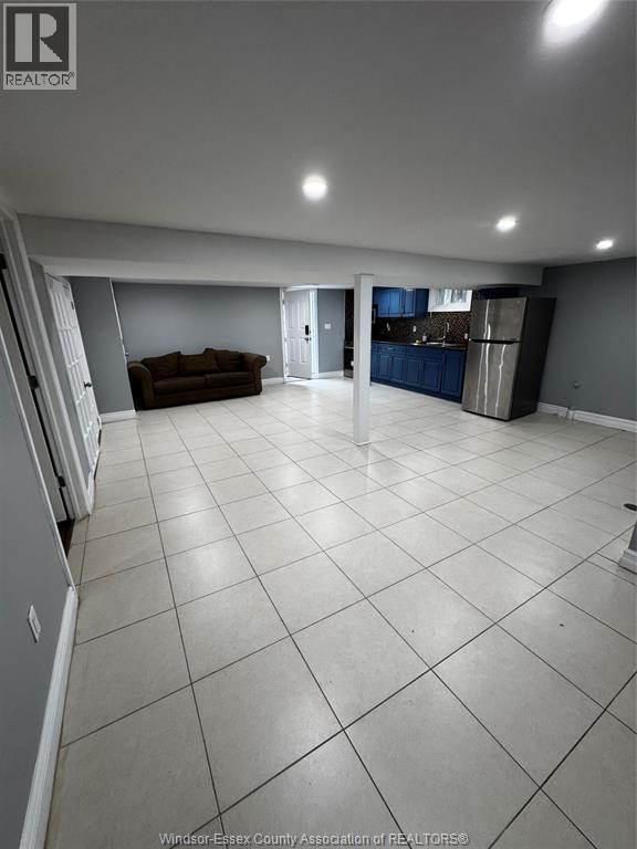 A spacious living room with a couch and a kitchen area in the background.
