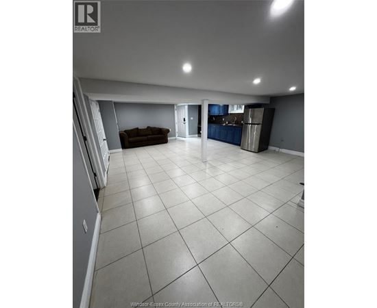 A spacious living room with a couch and a kitchen area in the background.