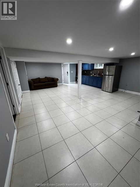 A spacious living room with a couch and a kitchen area in the background.