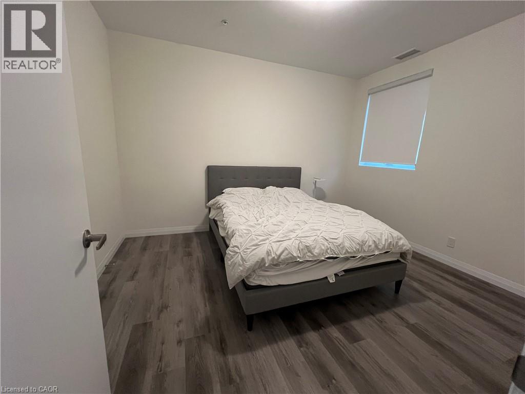 A bedroom with a bed, wooden floors, and a window.