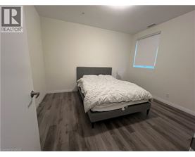A bedroom with a bed, wooden floors, and a window.