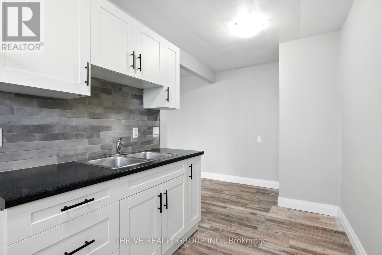 A kitchen with white cabinets and a black counter top.