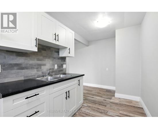 A kitchen with white cabinets and a black counter top.