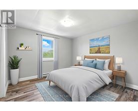 A bedroom with a large bed, a potted plant, and a painting on the wall.