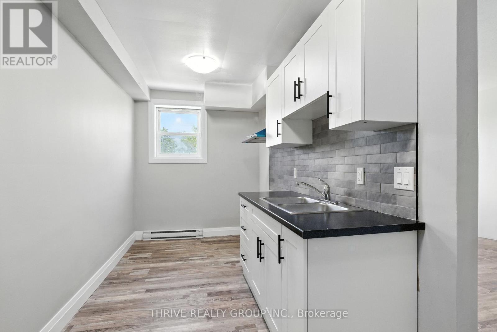 A kitchen with white cabinets and a black countertop.