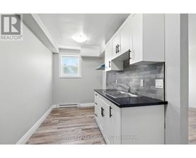 A kitchen with white cabinets and a black countertop.