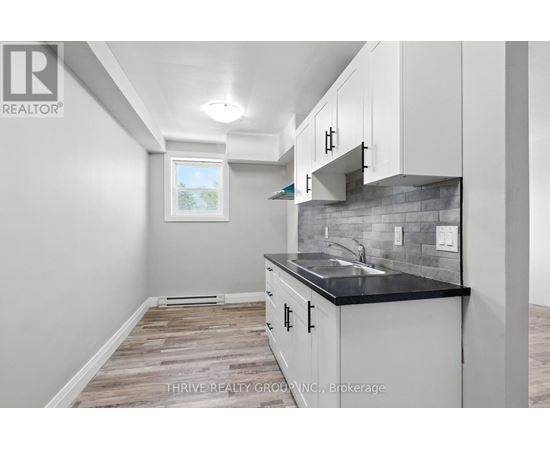 A kitchen with white cabinets and a black countertop.