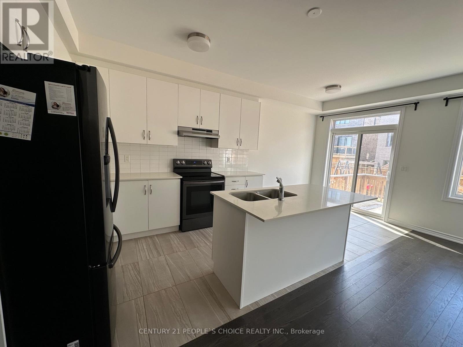 A kitchen with white cabinets and a black refrigerator.