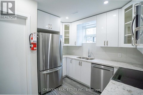 A kitchen with white cabinets and a stainless steel refrigerator.