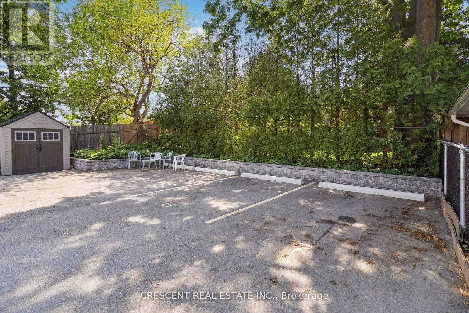 A gravel parking lot surrounded by trees and a wooden fence.