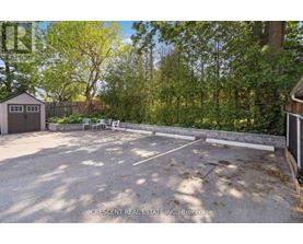 A gravel parking lot surrounded by trees and a wooden fence.
