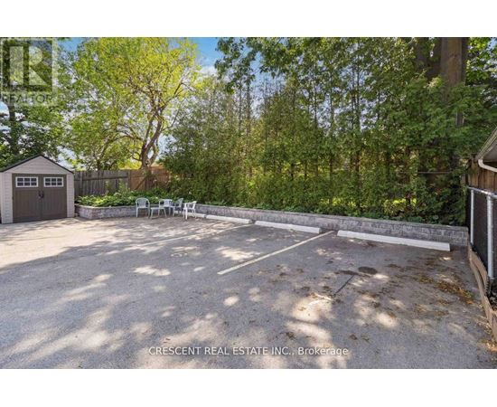 A gravel parking lot surrounded by trees and a wooden fence.