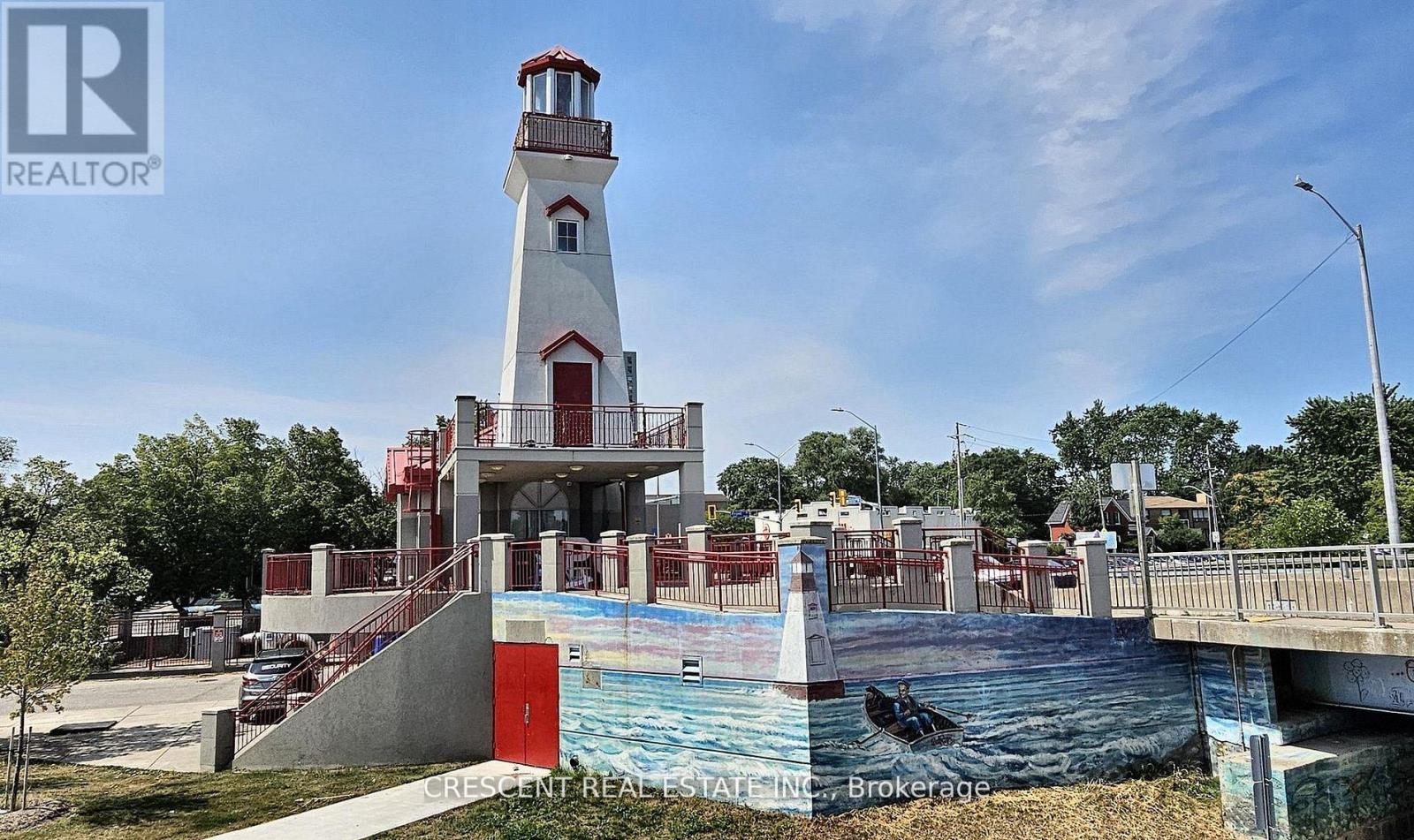 A lighthouse is in front of a pool and a bridge.