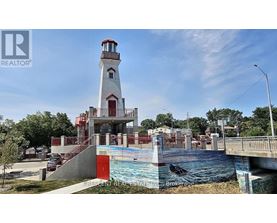 A lighthouse is in front of a pool and a bridge.