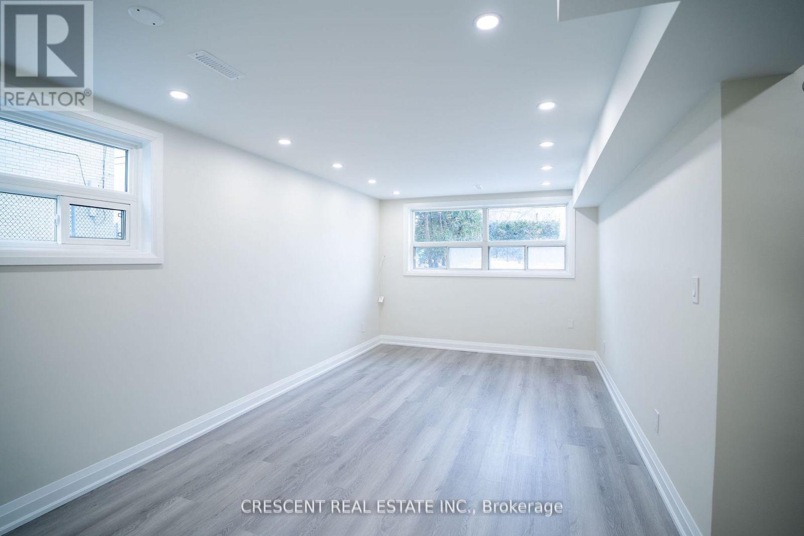 A spacious room with a window and wooden flooring.
