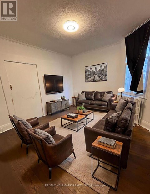 A living room with brown leather furniture and a flat screen TV mounted on the wall.