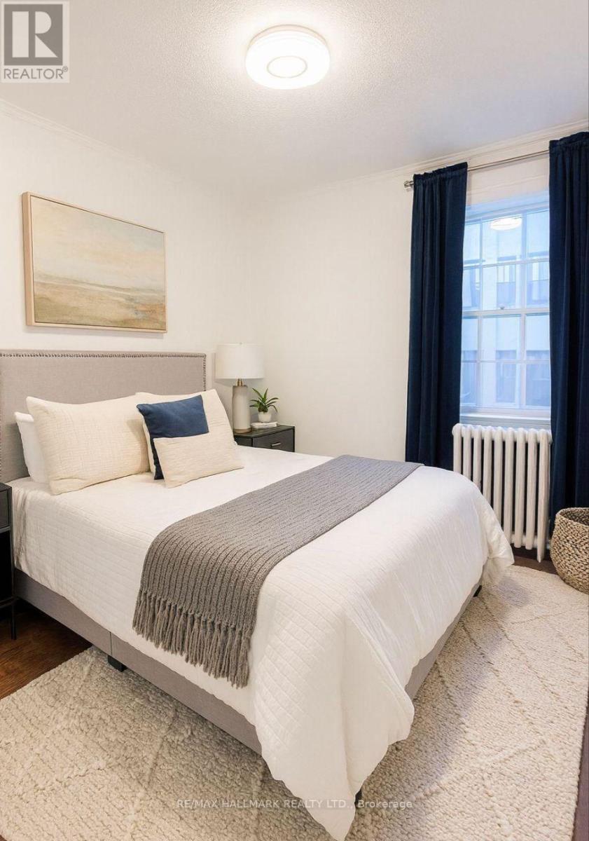 A bedroom with a large bed and a window with blue curtains.
