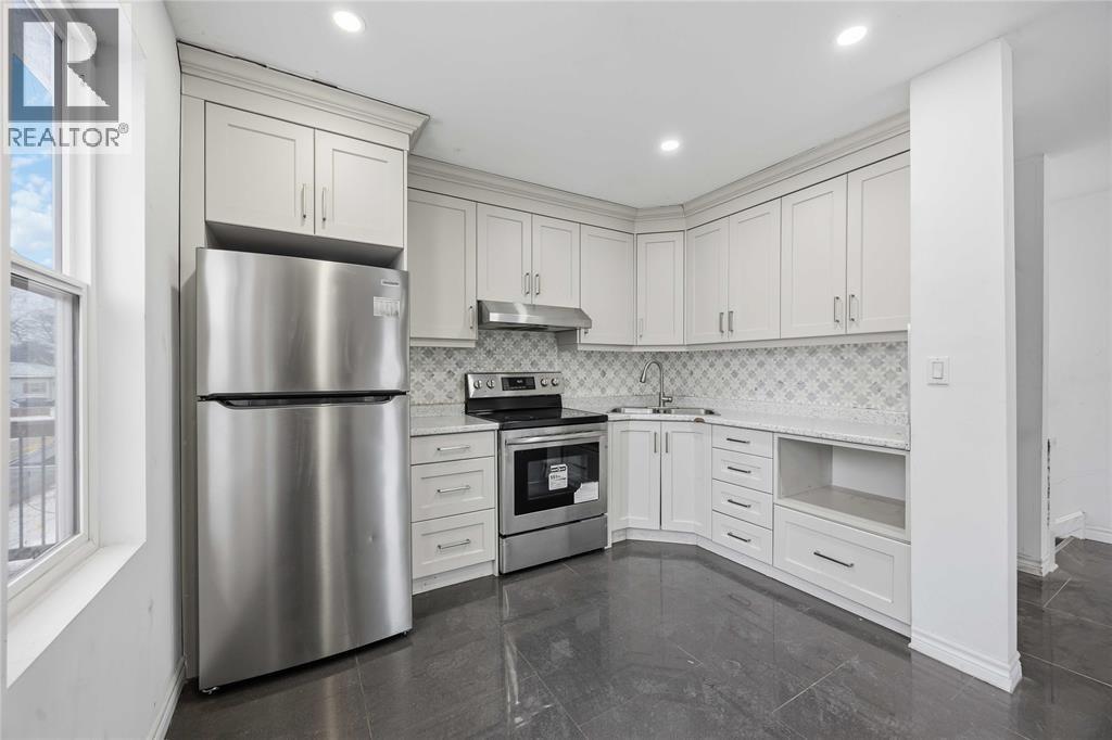 A modern kitchen with a stainless steel refrigerator and white cabinets.