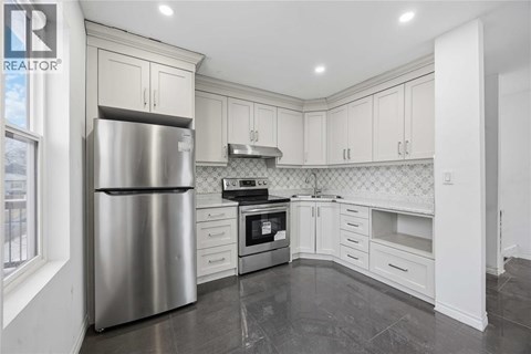 A modern kitchen with a stainless steel refrigerator and white cabinets.