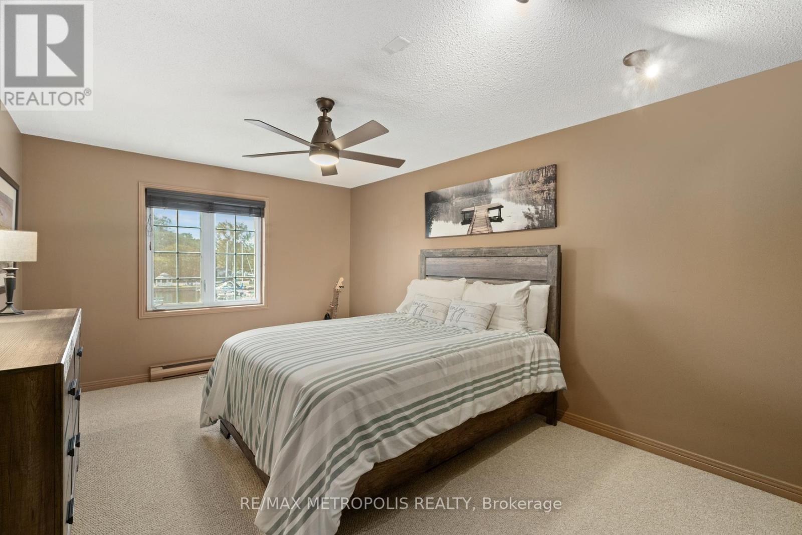 A bedroom with a bed, dresser, and ceiling fan.