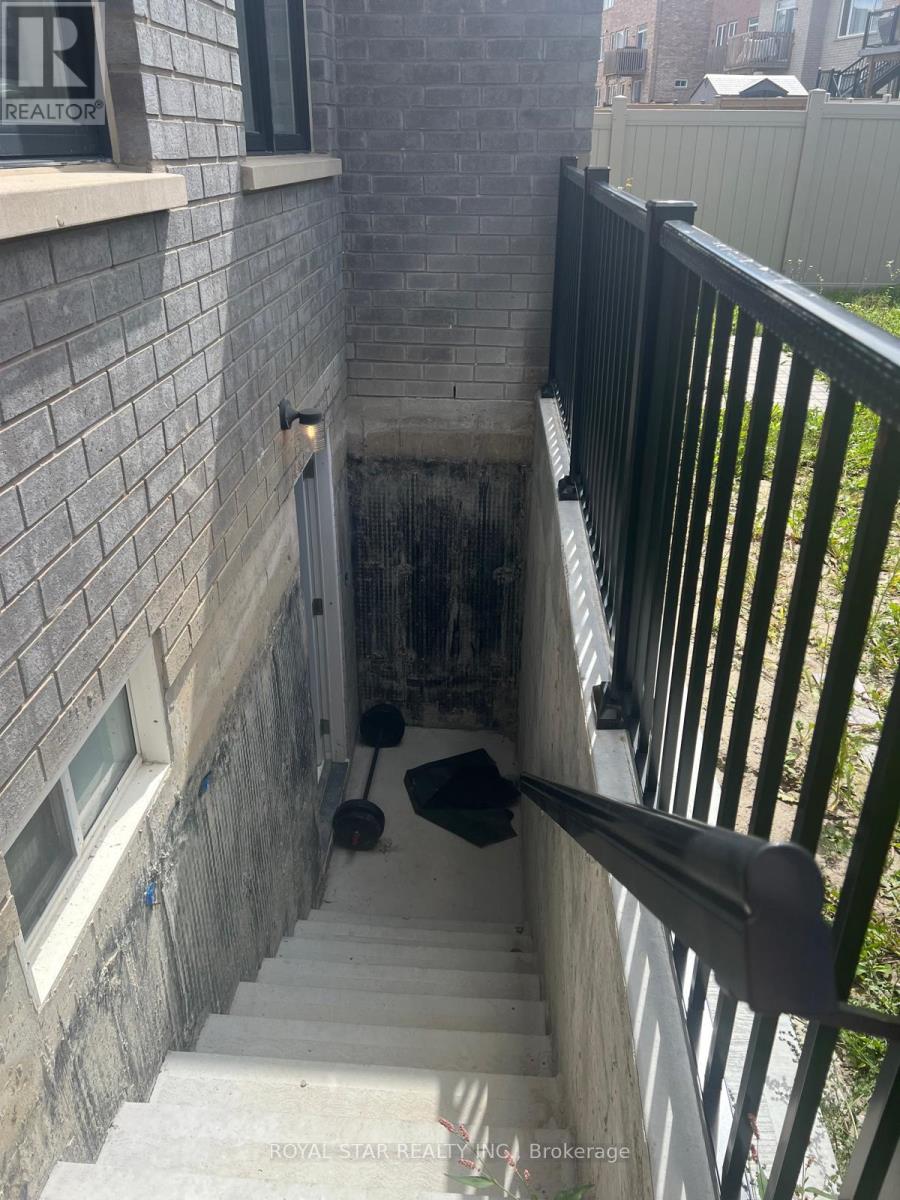 A staircase with a black railing and a brick wall.