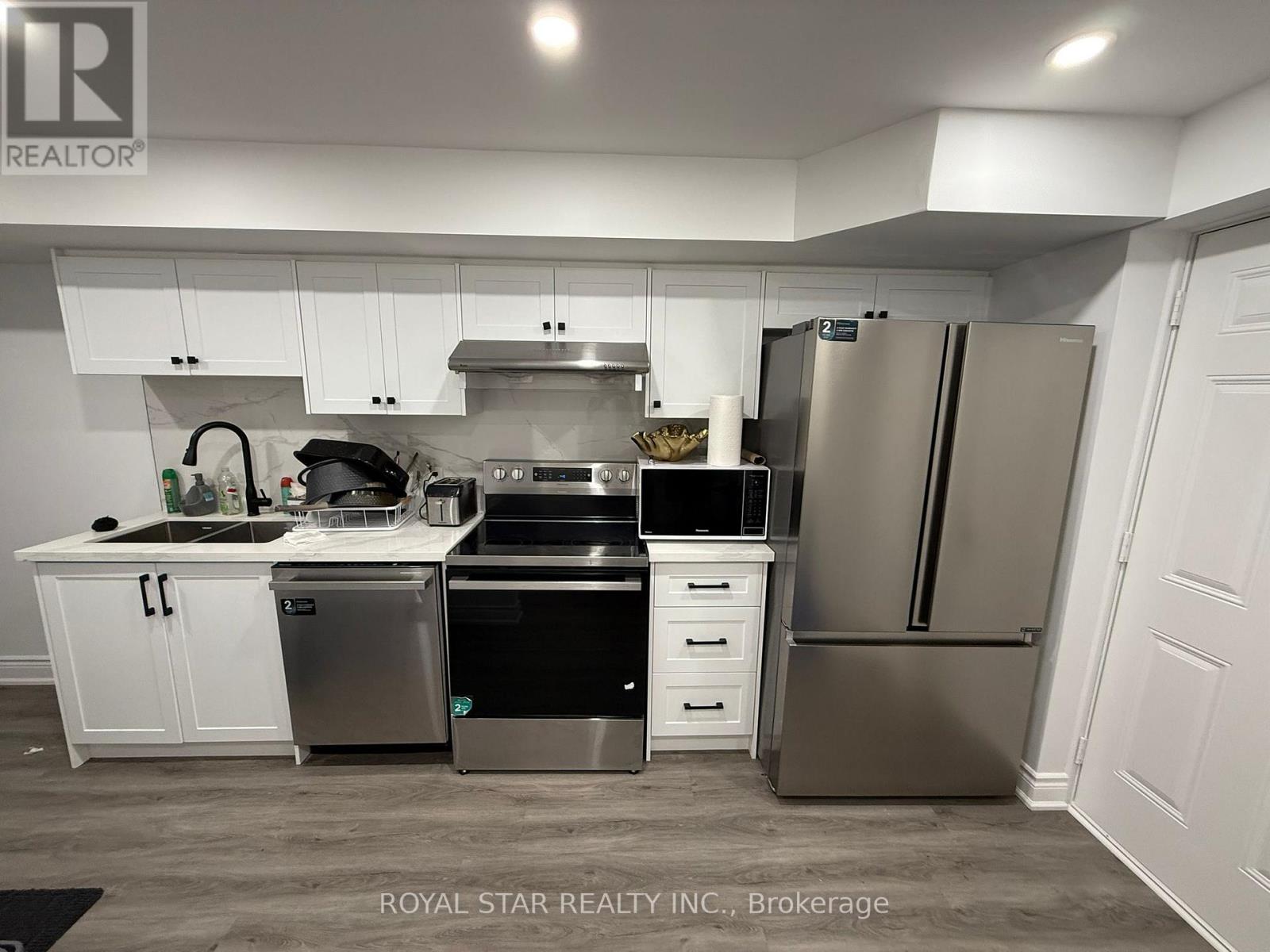 A kitchen with a refrigerator, sink, and stove.