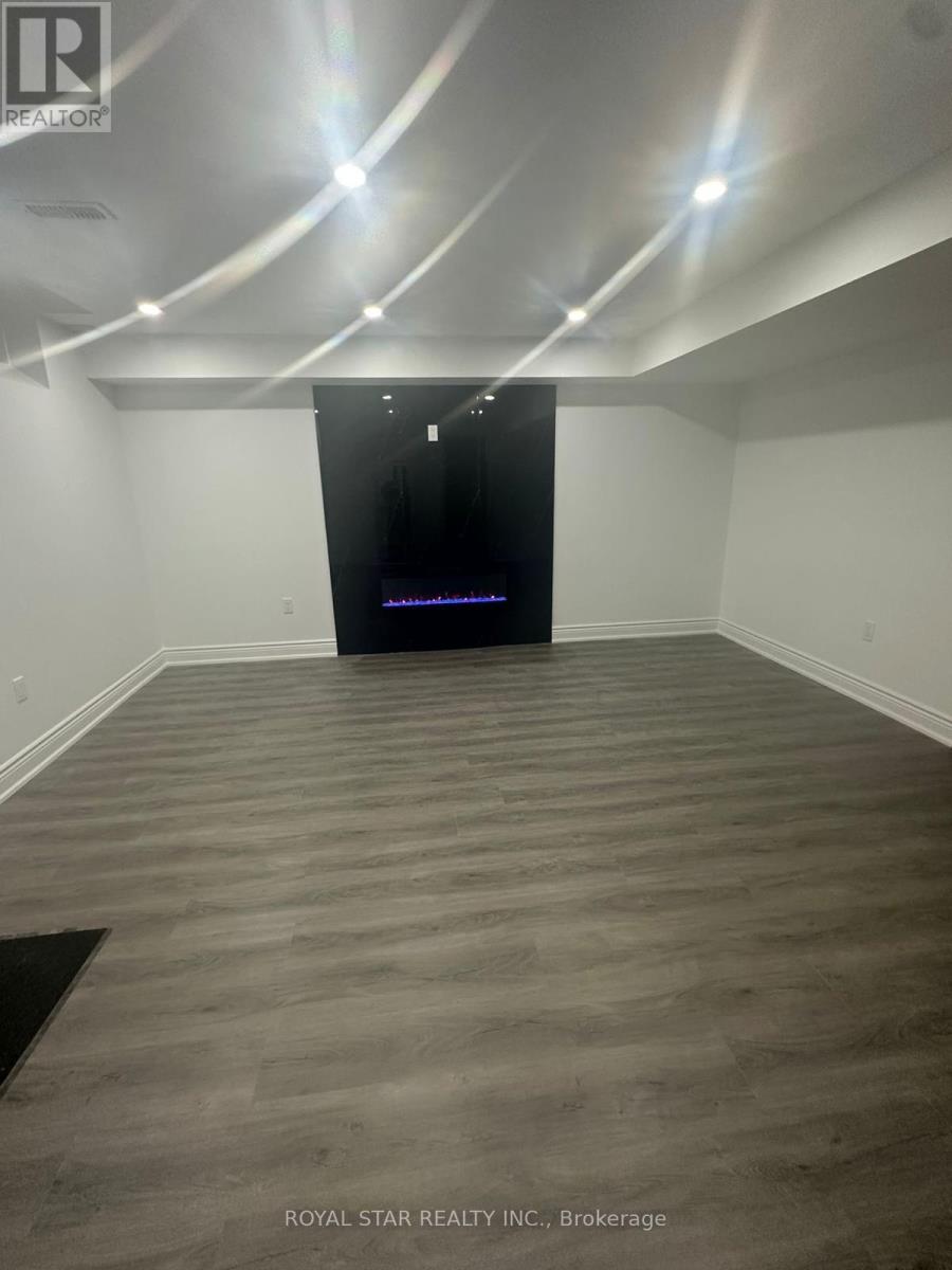 A spacious room with wooden flooring and a black door at the end.