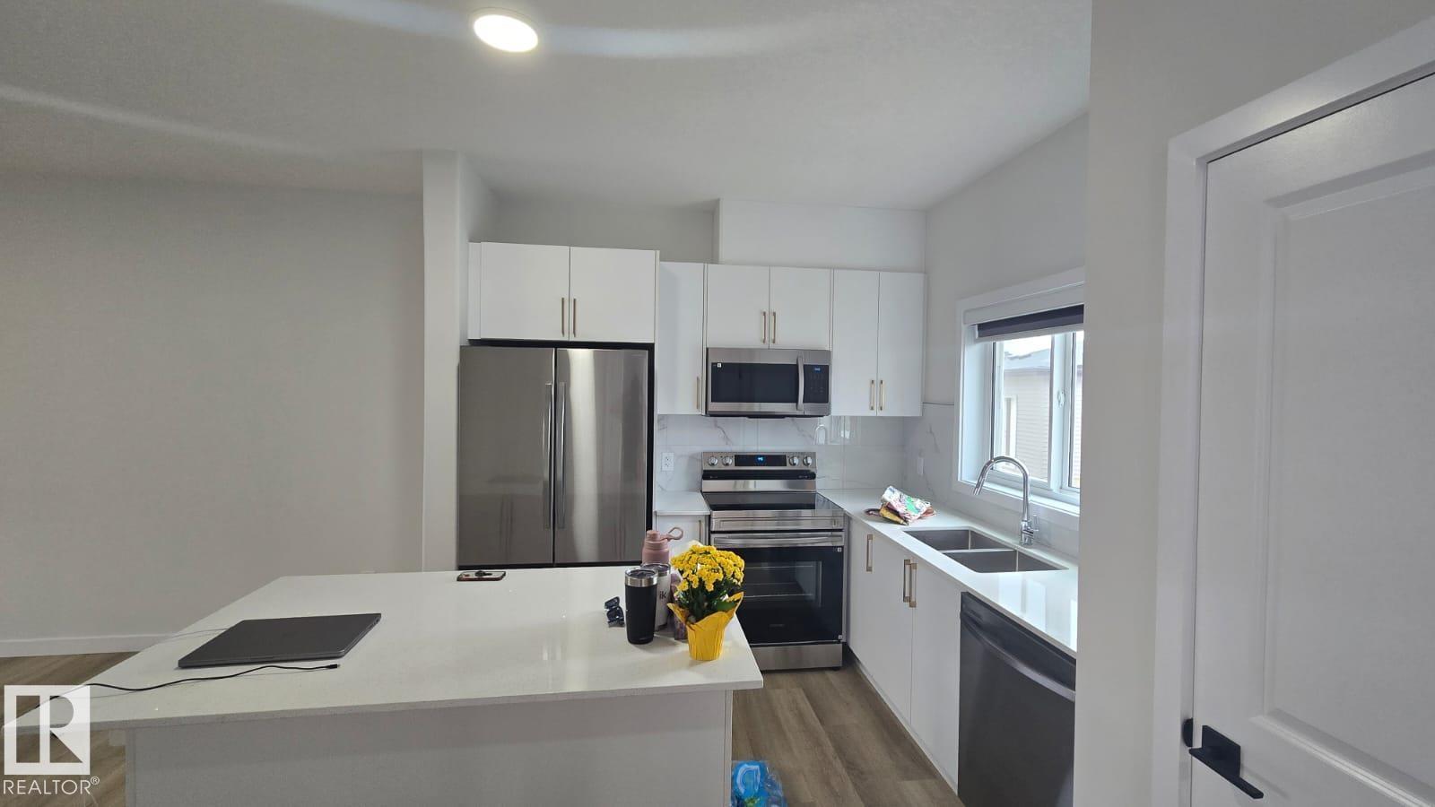 A kitchen with white cabinets and a stainless steel refrigerator.