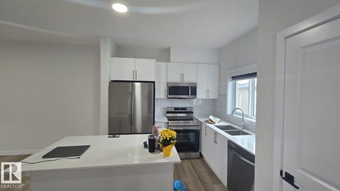 A kitchen with white cabinets and a stainless steel refrigerator.