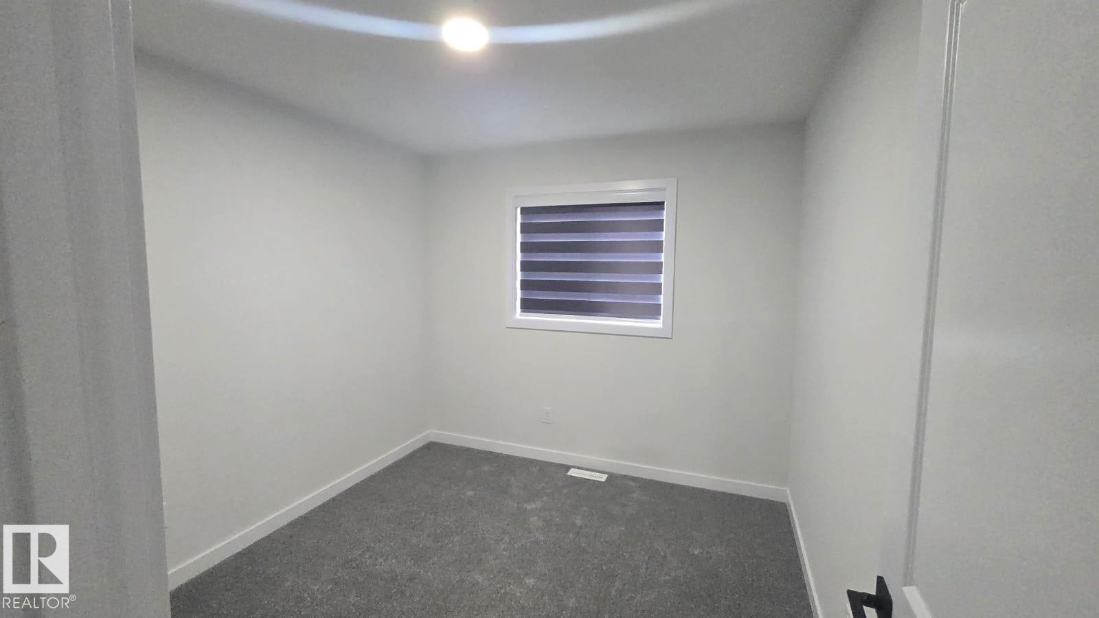 A bedroom with a carpeted floor and white walls.