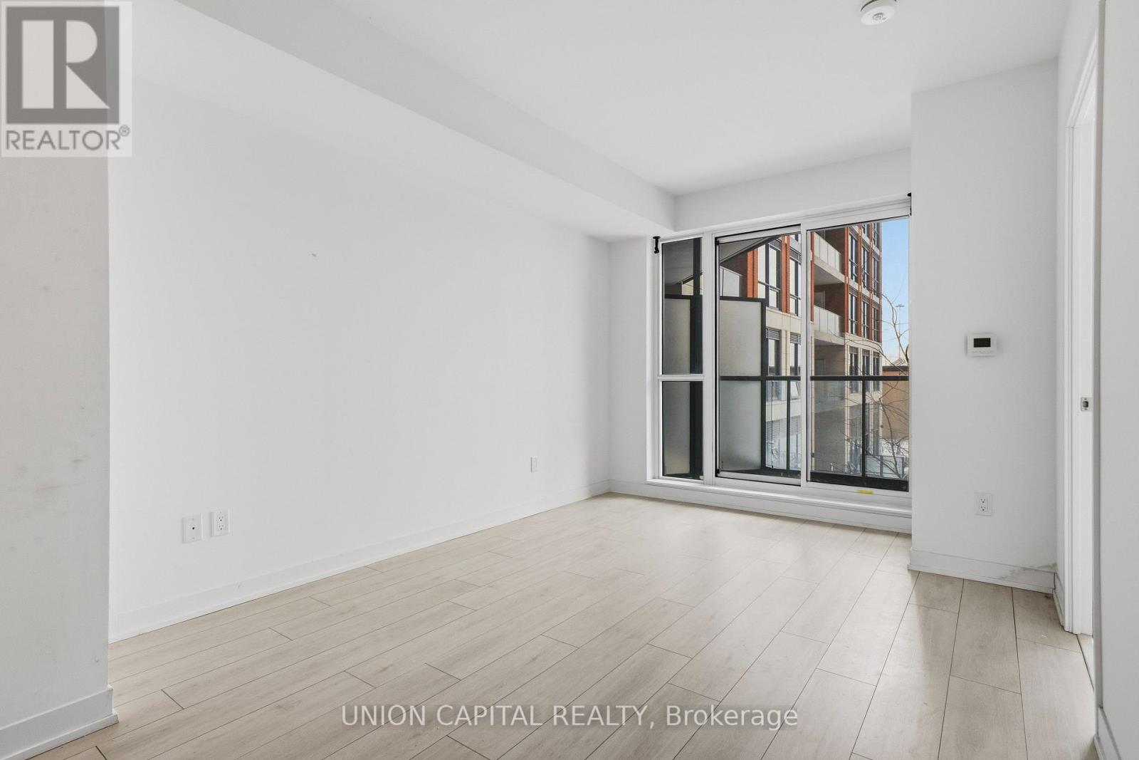 A white room with a window and wooden flooring.
