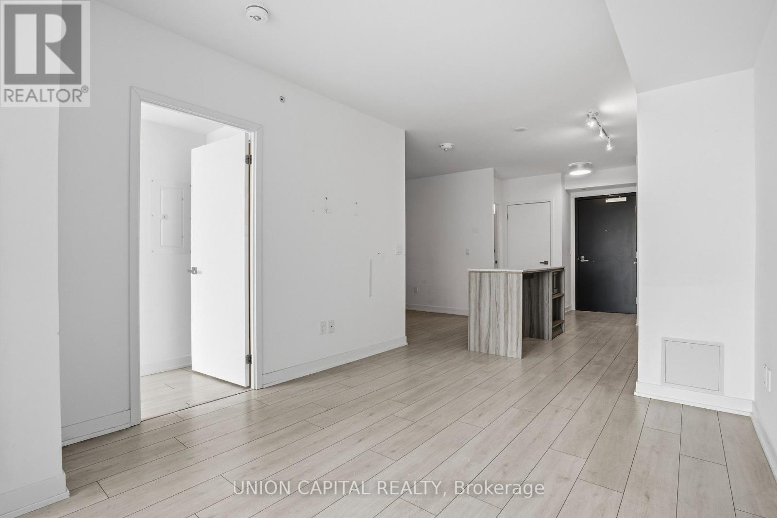 A spacious room with a desk and a doorway leading to another room.