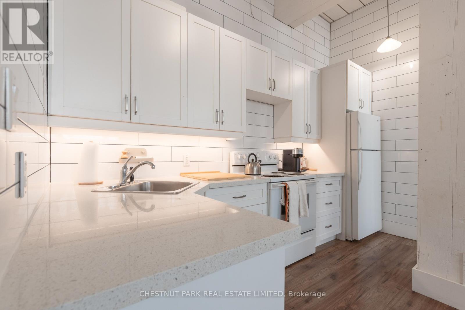 A modern kitchen with white cabinets and a marble countertop.