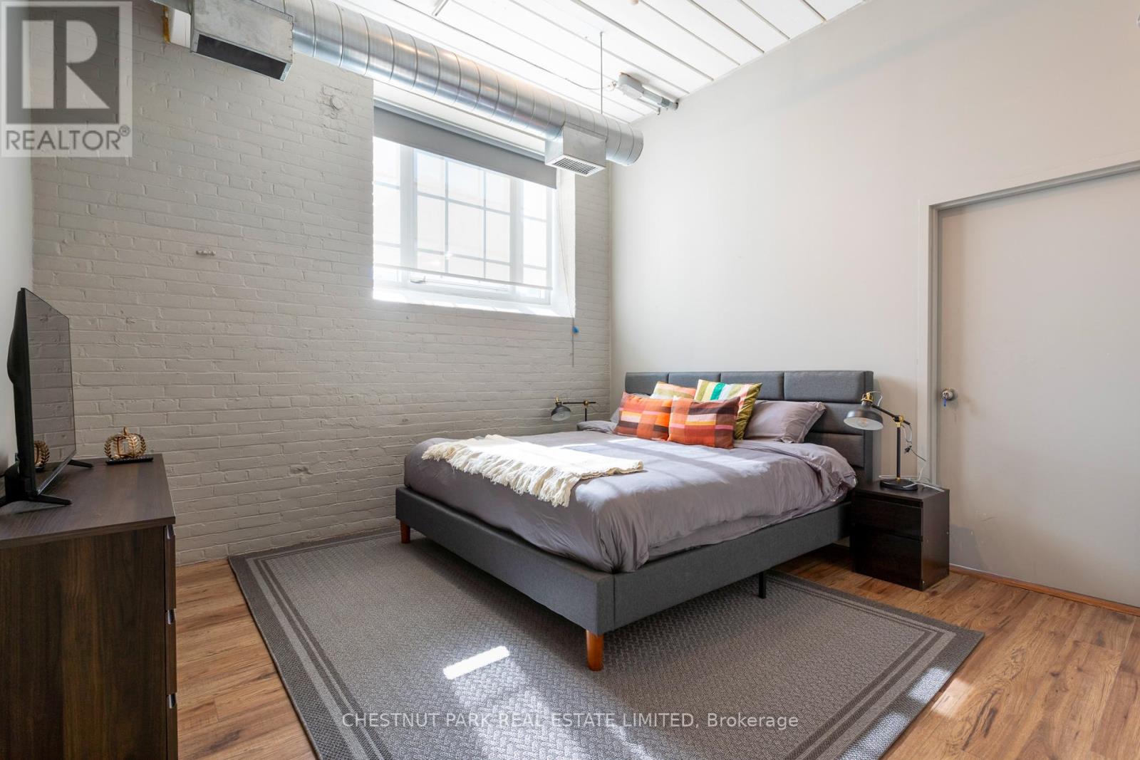 A bedroom with a bed, nightstand, and a tv.