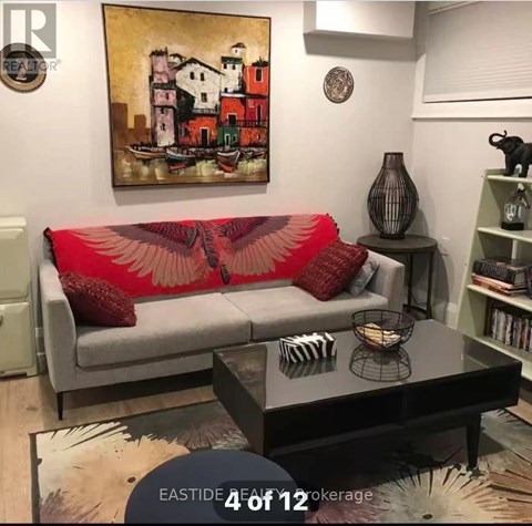 A living room with a grey couch and a painting on the wall.