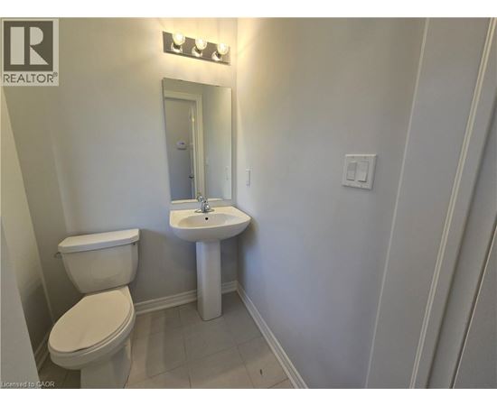 A white toilet and sink in a small bathroom.