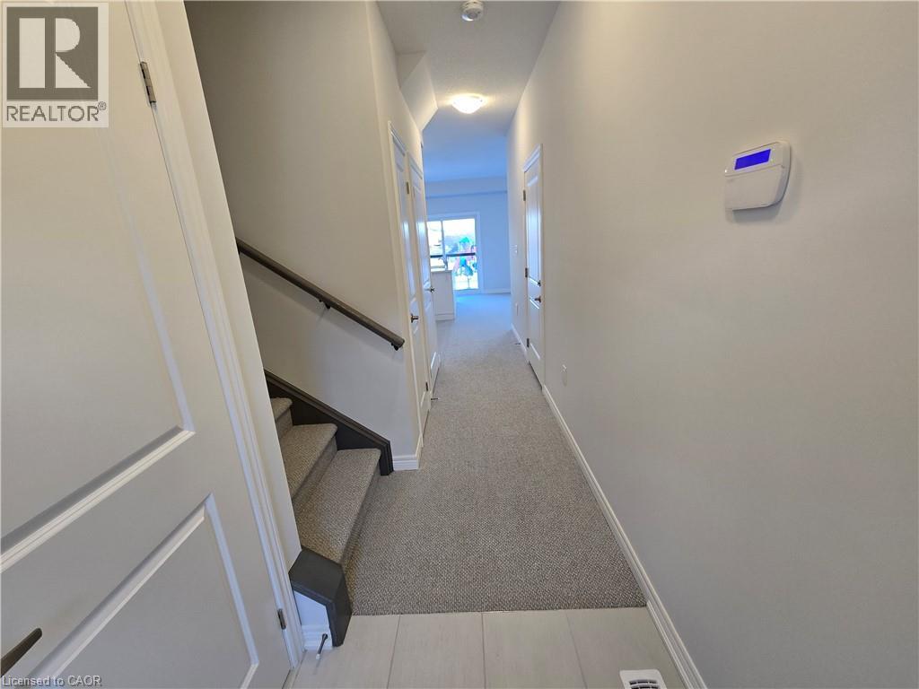 A hallway with a staircase and a wall-mounted device on the wall.