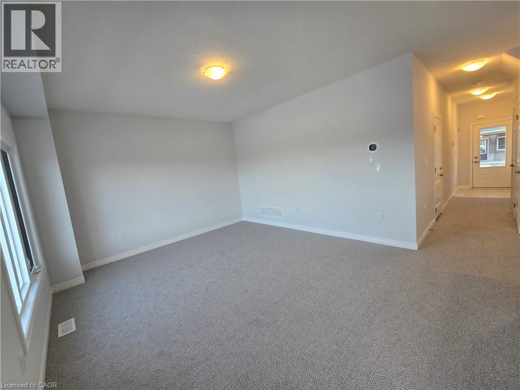 A spacious room with a carpeted floor and a single light fixture on the ceiling.