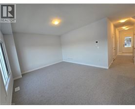 A spacious room with a carpeted floor and a single light fixture on the ceiling.