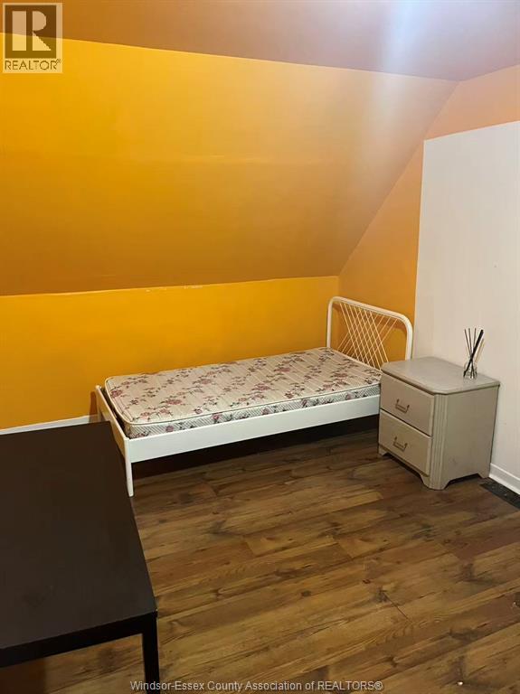 A bedroom with a bed, nightstand and chair.
