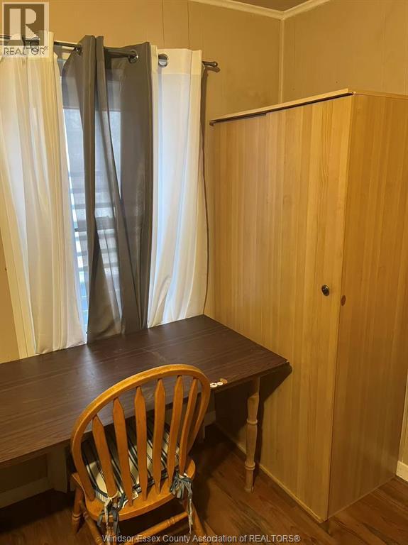 A wooden chair is in front of a table with a curtain behind it.