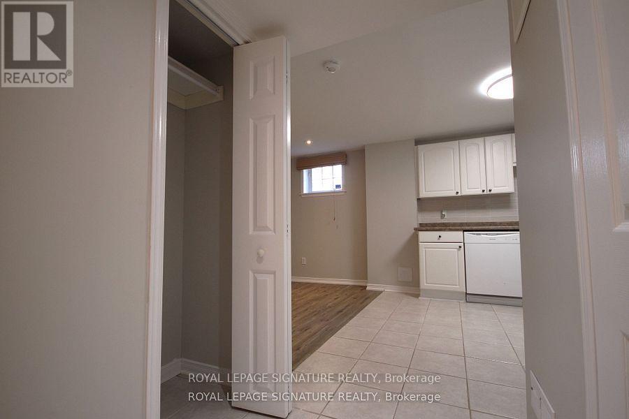A white doorway leads to a kitchen with white cabinets and a white dishwasher.