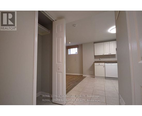 A white doorway leads to a kitchen with white cabinets and a white dishwasher.