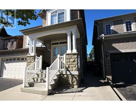 A house with a stone pillar and a white railing.