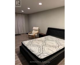 A bed with a Serta mattress is in a room with a chair.