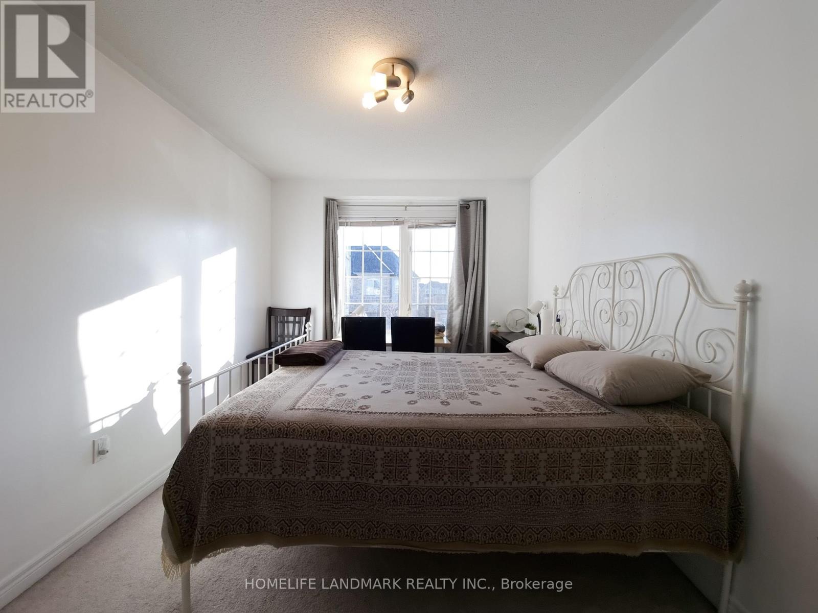 A bedroom with a large bed and a window letting in sunlight.