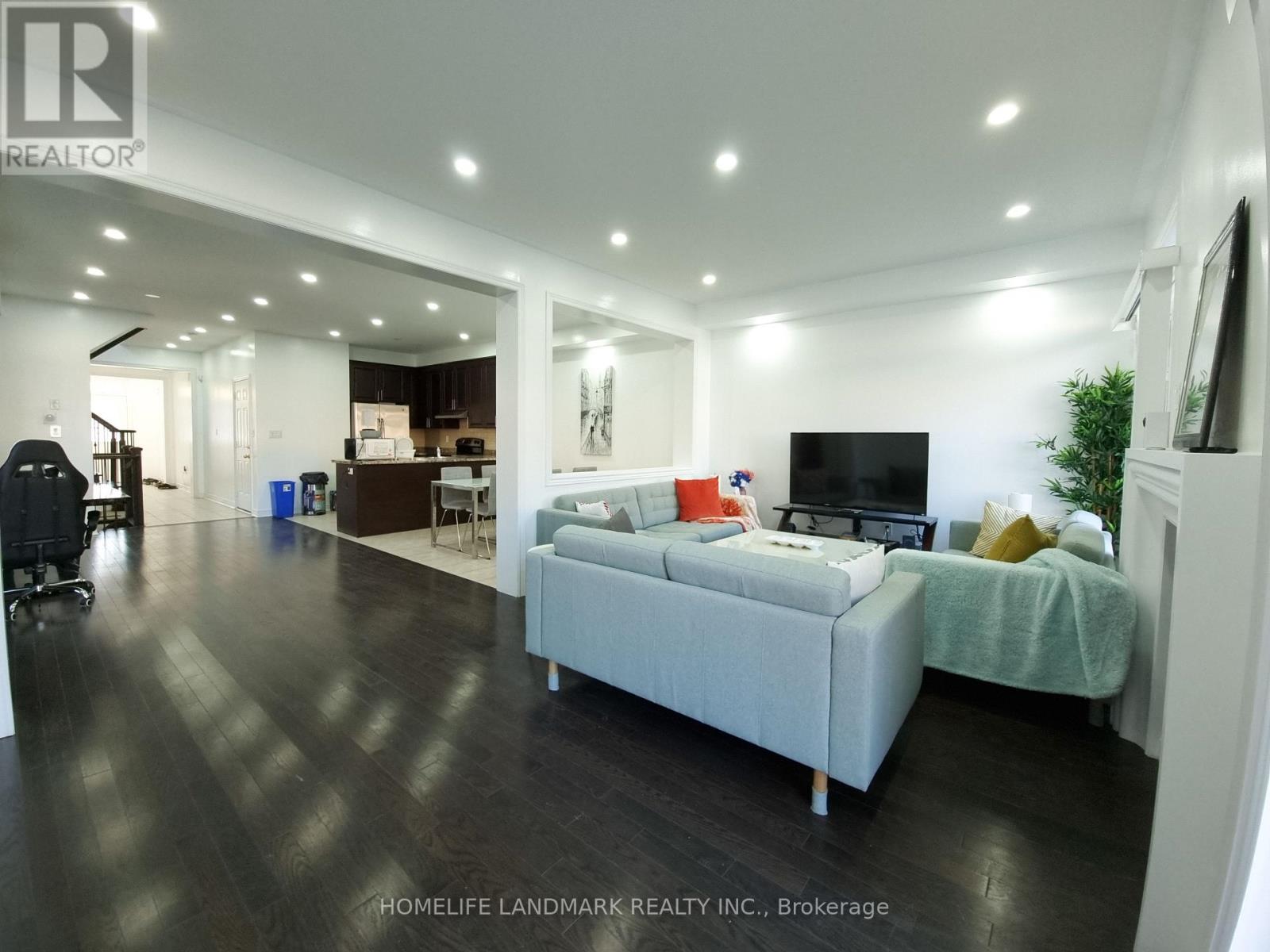 A spacious living room with a grey sofa and a television.