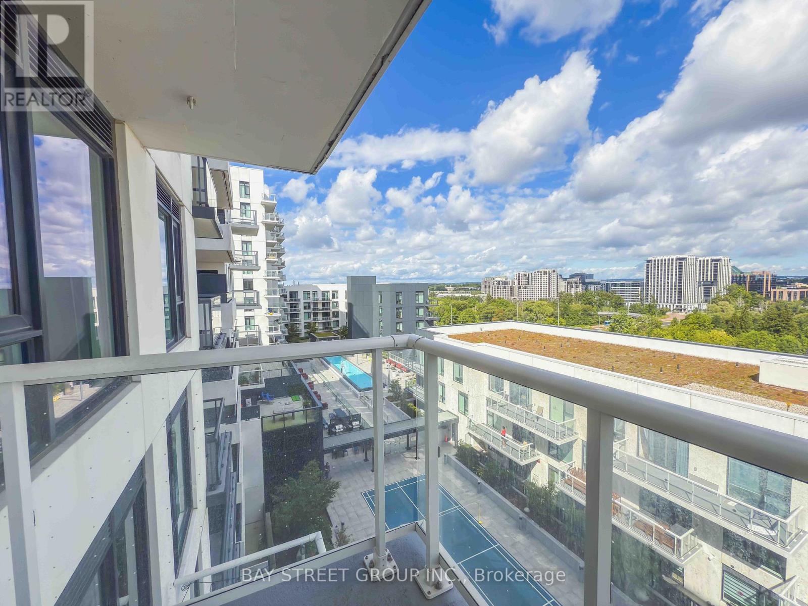 A balcony overlooks a cityscape with buildings and a pool.