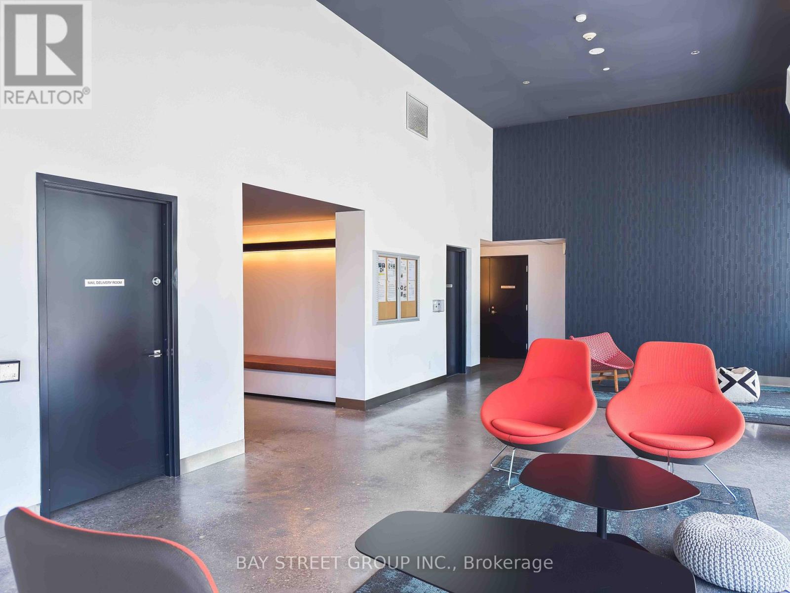 A modern office space with a black door, two red chairs, and a round table.